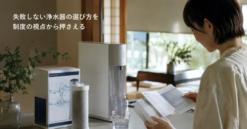 キッチンで浄水器や交換カートリッジを前に、書類を確認しながら選び方を検討する女性