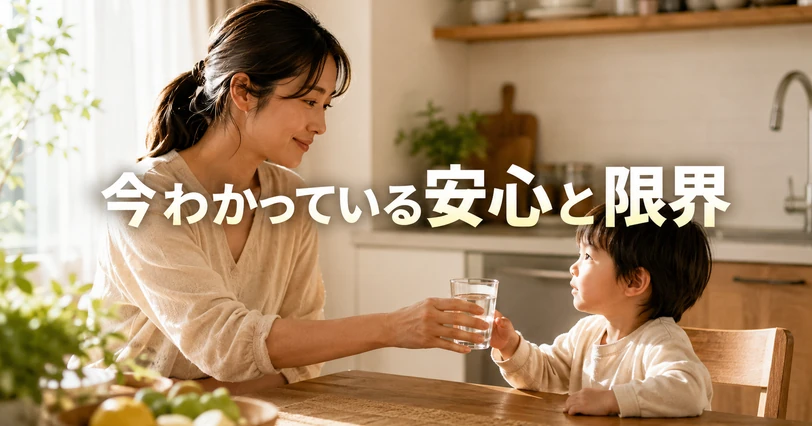 母親が子どもに水の入ったコップを手渡す、安心感のあるキッチンの様子を写した写真