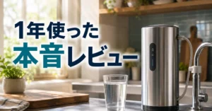 朝の光が差すキッチンに置かれたステンレス製の据置型浄水器とグラスの水。「1年使った本音レビュー」の文字入りアイキャッチ