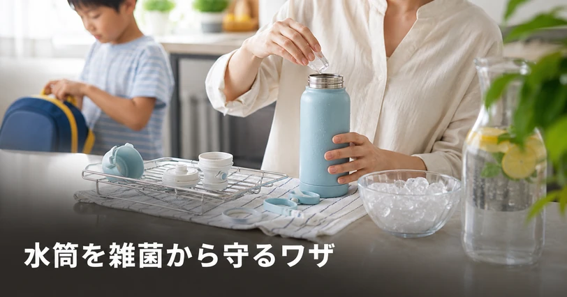 洗った水筒のパッキンと飲み口を水切りかごで乾かし、子どもが支度をしている夏の水筒衛生のイメージ
